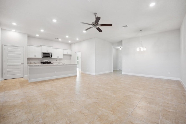 unfurnished living room with ceiling fan with notable chandelier and sink