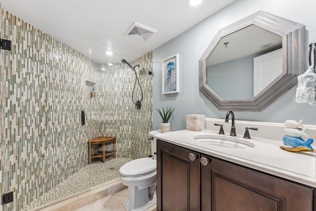 bathroom with tile patterned floors, vanity, toilet, and a tile shower