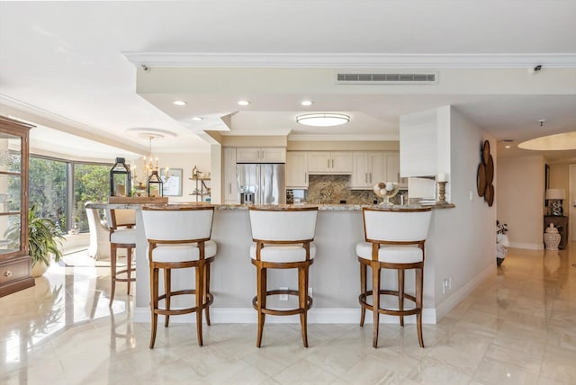 kitchen featuring kitchen peninsula, stainless steel refrigerator with ice dispenser, tasteful backsplash, crown molding, and stone countertops