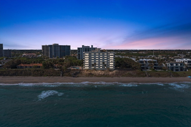 aerial view at dusk with a water view and a view of the beach