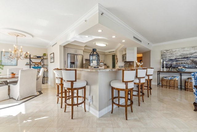 kitchen with kitchen peninsula, appliances with stainless steel finishes, decorative backsplash, decorative light fixtures, and a notable chandelier