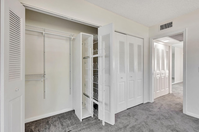 unfurnished bedroom with carpet floors, a textured ceiling, and multiple closets