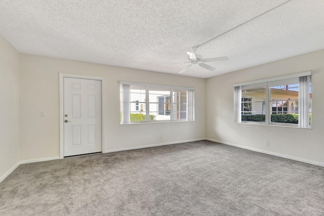 carpeted empty room with ceiling fan, a healthy amount of sunlight, and a textured ceiling