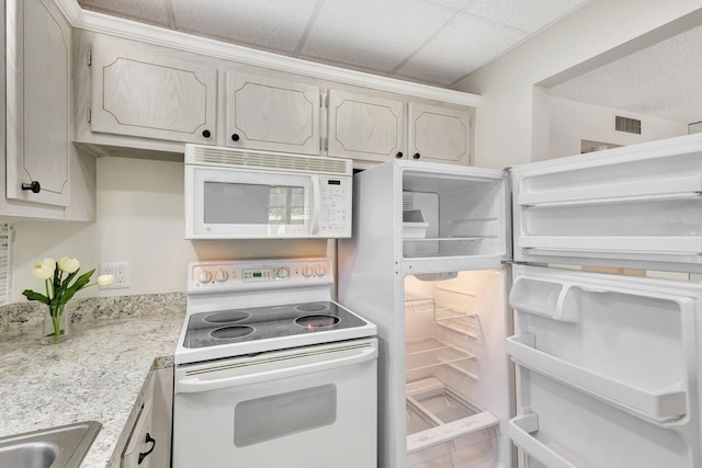 kitchen with tile patterned flooring, white appliances, a drop ceiling, and sink