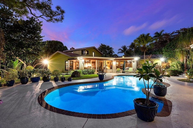 pool at dusk featuring a patio