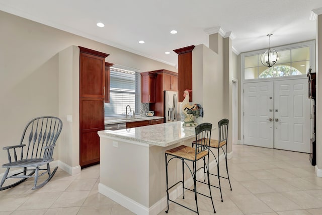 kitchen with appliances with stainless steel finishes, light stone counters, ornamental molding, sink, and decorative light fixtures