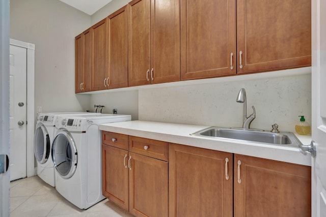 laundry area featuring washer and dryer, cabinets, light tile patterned floors, and sink