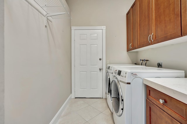 laundry area with cabinets, light tile patterned floors, and washing machine and dryer