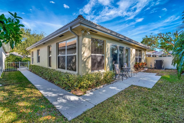 view of side of property with a patio, central AC, and a lawn