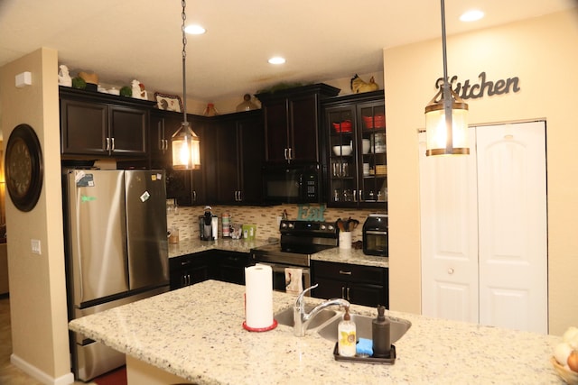 kitchen with sink, light stone counters, backsplash, decorative light fixtures, and black appliances