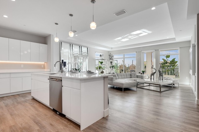 kitchen featuring decorative light fixtures, a tray ceiling, white cabinetry, and light hardwood / wood-style flooring