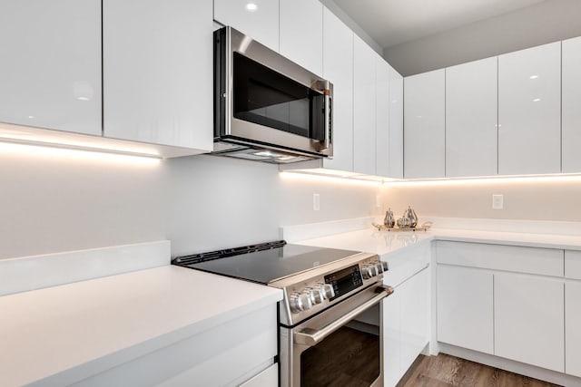 kitchen featuring white cabinets, appliances with stainless steel finishes, and light hardwood / wood-style flooring