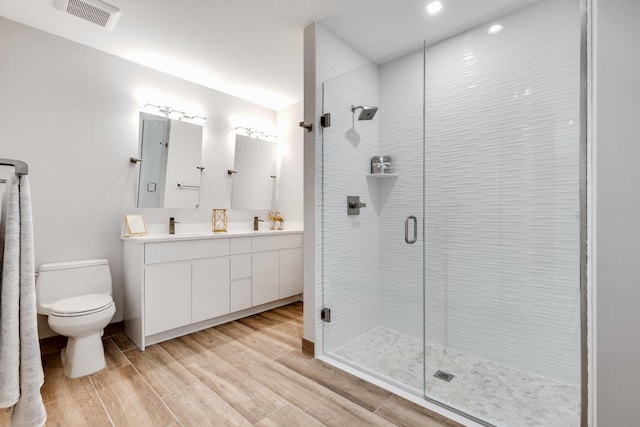 bathroom featuring toilet, vanity, an enclosed shower, and hardwood / wood-style flooring