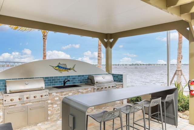 view of patio featuring area for grilling, a water view, a wet bar, and grilling area