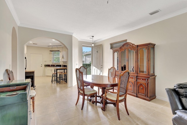 tiled dining room with a textured ceiling and crown molding