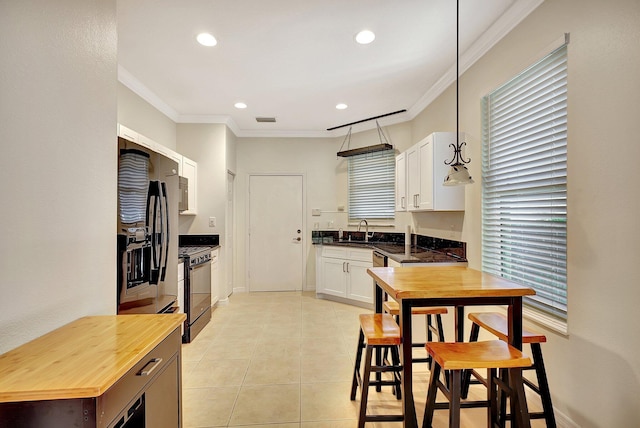 kitchen featuring sink, range with gas cooktop, crown molding, decorative light fixtures, and white cabinets