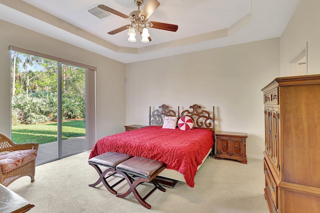 bedroom with light carpet, access to outside, a tray ceiling, and ceiling fan