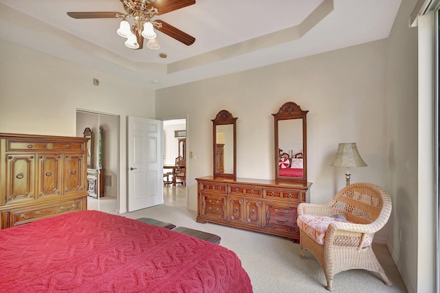 bedroom with a closet, a raised ceiling, and ceiling fan