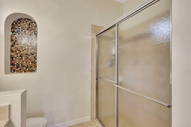 bathroom with tile patterned flooring, toilet, and a shower with door