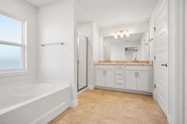 bathroom featuring plus walk in shower, vanity, and a healthy amount of sunlight