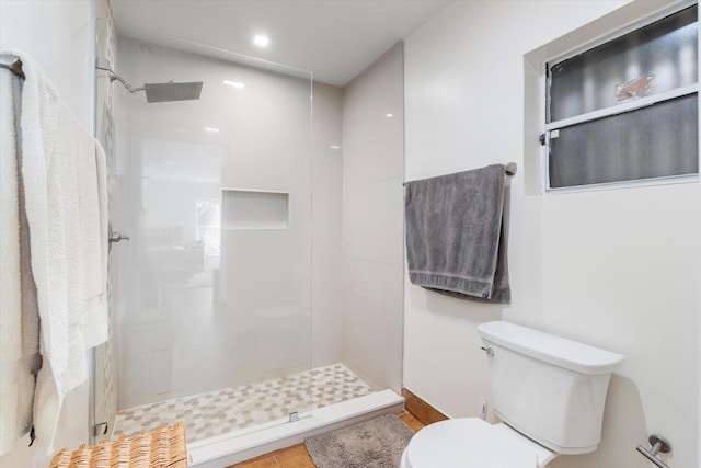 bathroom with a tile shower and toilet