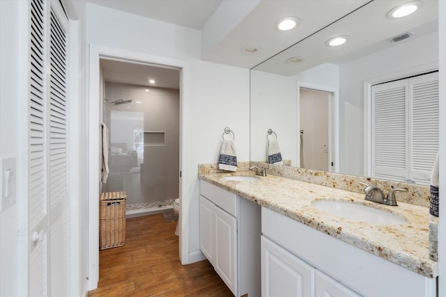 bathroom featuring tiled shower, wood-type flooring, vanity, and toilet