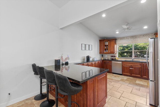 kitchen featuring ceiling fan, sink, stainless steel appliances, kitchen peninsula, and a kitchen bar