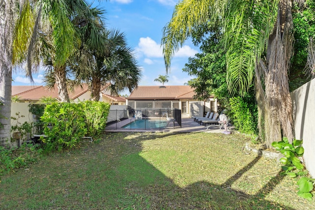 rear view of property with a patio area, a fenced in pool, and a yard