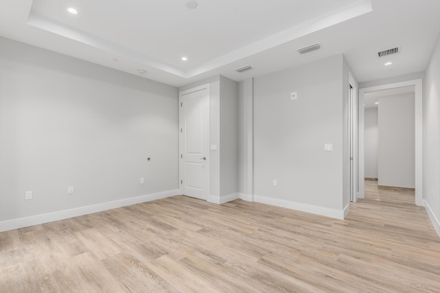 unfurnished room featuring a raised ceiling and light wood-type flooring