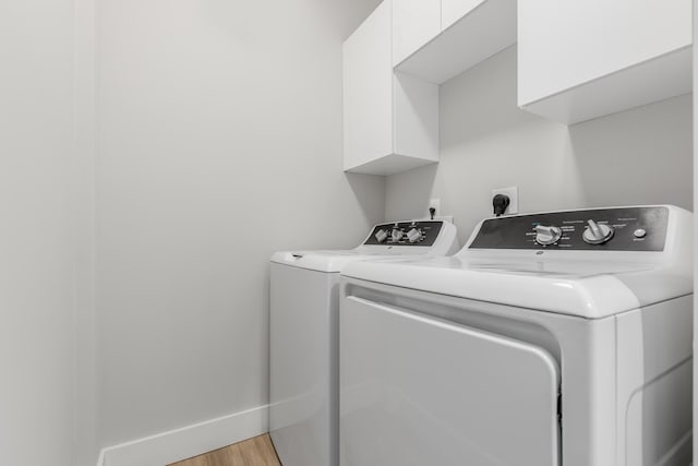 laundry room featuring cabinets, light hardwood / wood-style floors, and washing machine and clothes dryer