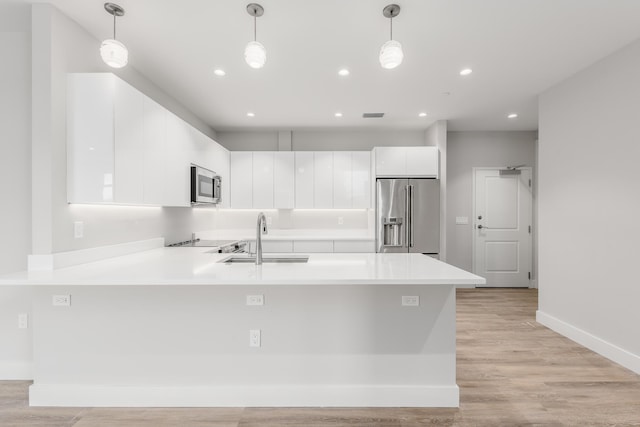 kitchen with sink, light wood-type flooring, stainless steel appliances, and hanging light fixtures