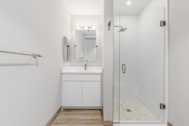 bathroom with hardwood / wood-style flooring, vanity, and a shower with door