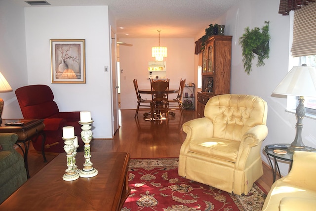 living room with hardwood / wood-style floors, a textured ceiling, and an inviting chandelier