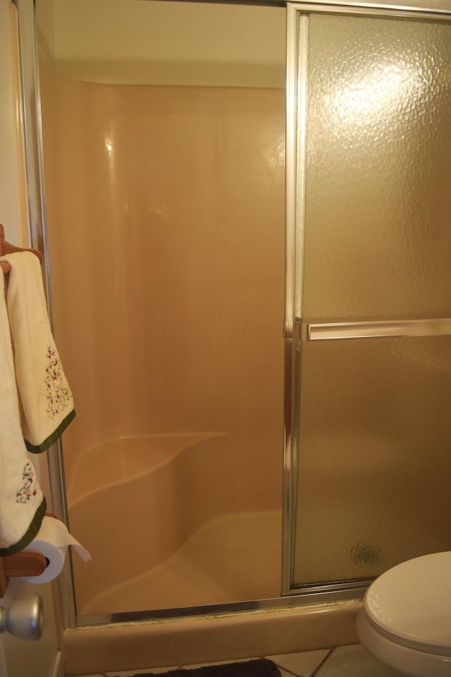 bathroom with tile patterned flooring, toilet, and walk in shower