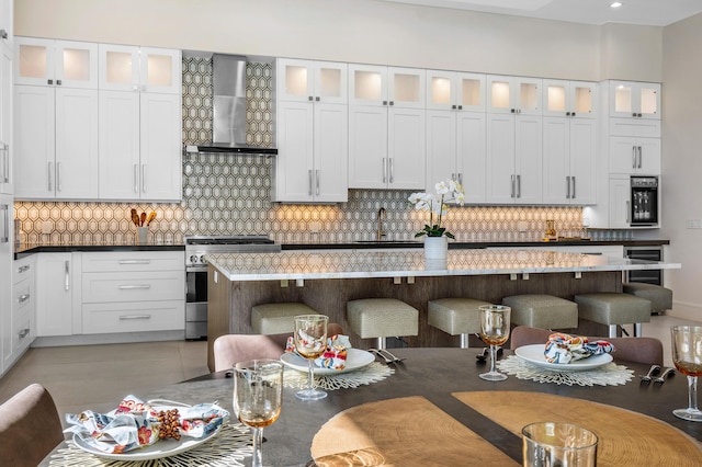 kitchen with white cabinetry, wall chimney range hood, and high end stainless steel range oven