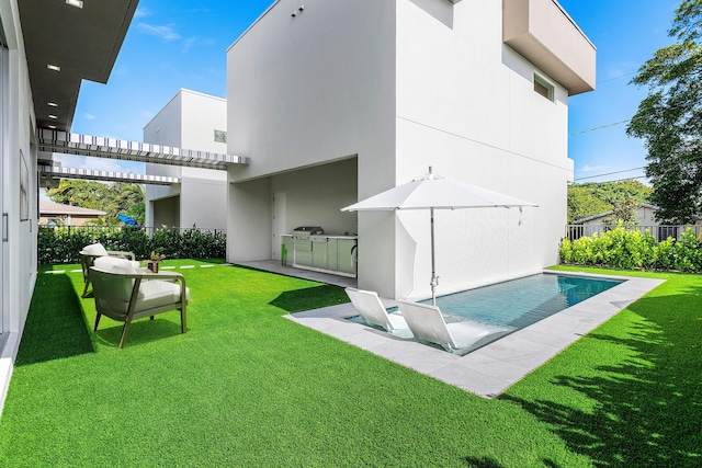 rear view of house with a lawn, exterior kitchen, and a fenced in pool