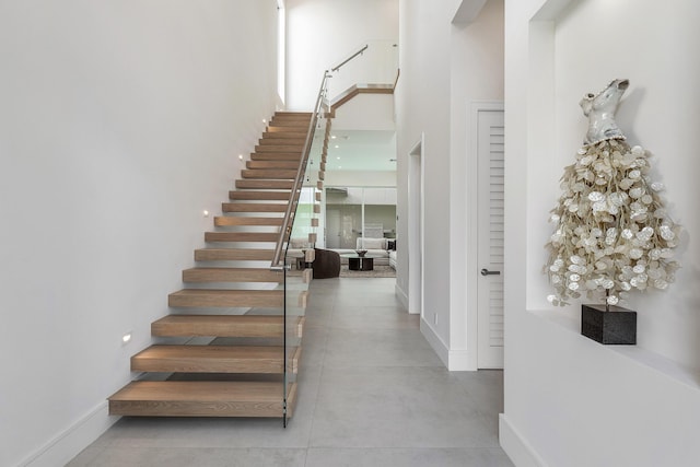 stairs featuring a towering ceiling and concrete floors