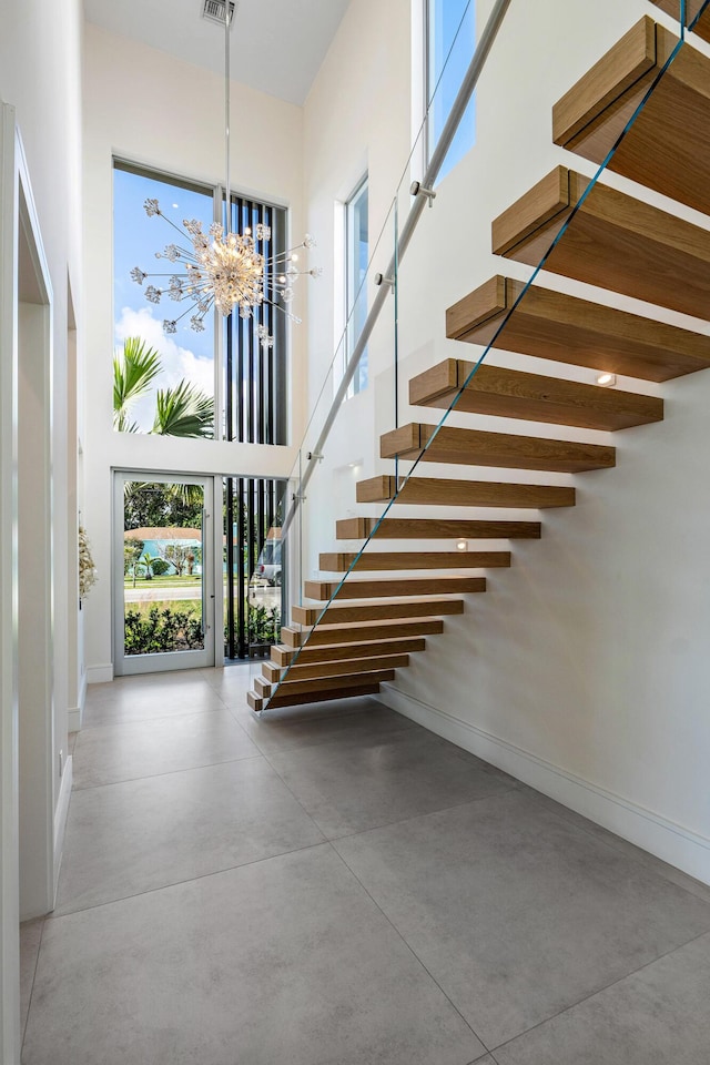 entryway featuring concrete floors, a high ceiling, and an inviting chandelier