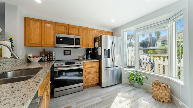 kitchen featuring light stone countertops, sink, and stainless steel appliances