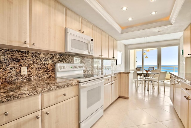 kitchen with white appliances, a water view, decorative backsplash, light brown cabinetry, and a tray ceiling