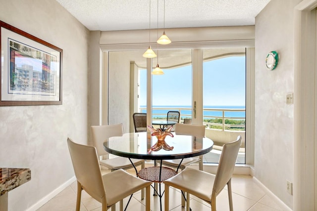 tiled dining space featuring a wealth of natural light, a water view, and a textured ceiling