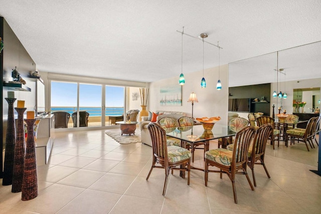 dining space featuring a water view, light tile patterned floors, and a textured ceiling