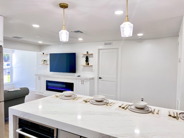 kitchen featuring open shelves, visible vents, light stone countertops, and pendant lighting