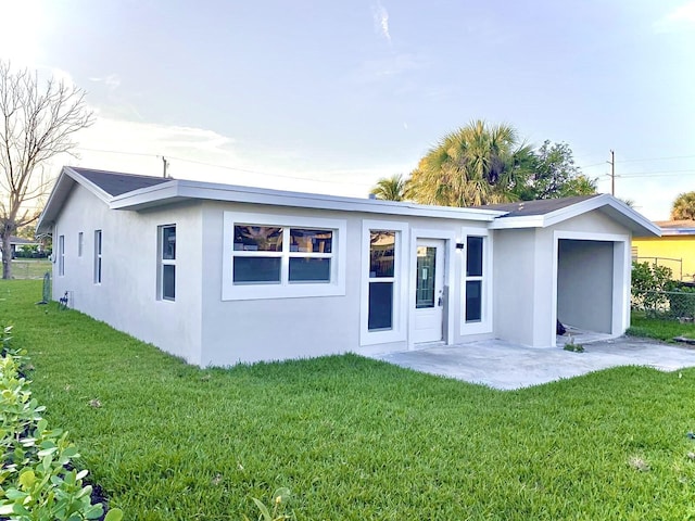 rear view of property featuring a yard and stucco siding