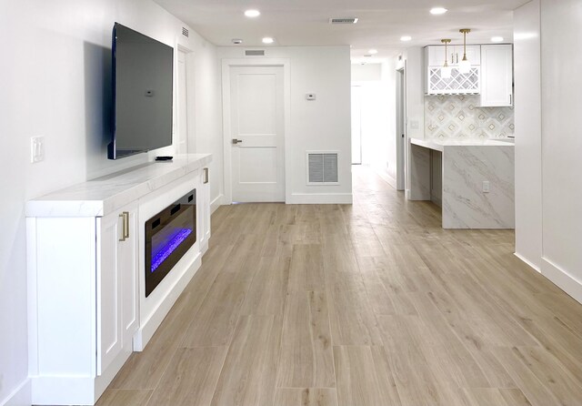 unfurnished living room featuring baseboards, light wood-type flooring, visible vents, and recessed lighting