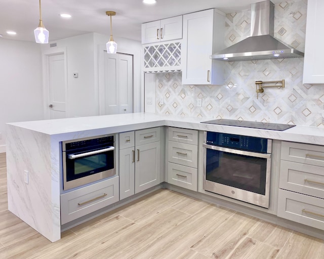 kitchen with wall chimney exhaust hood, gray cabinets, and oven