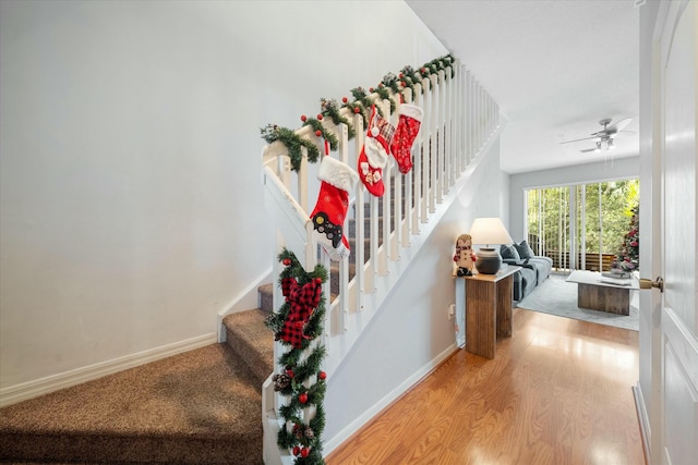 stairway with wood-type flooring and ceiling fan