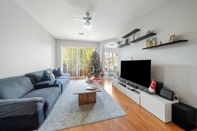 living room featuring a textured ceiling, light hardwood / wood-style floors, and ceiling fan