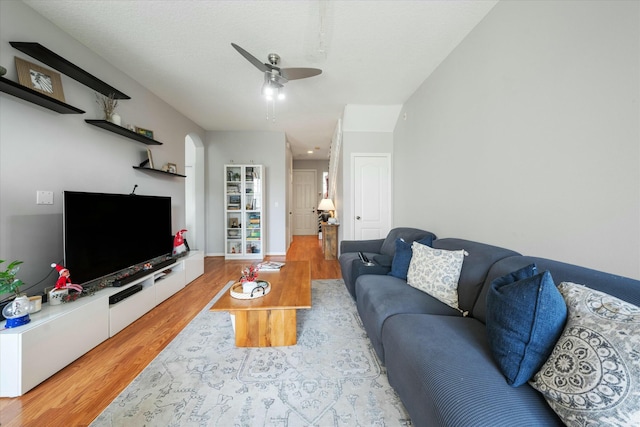 living room featuring ceiling fan, light hardwood / wood-style floors, and a textured ceiling