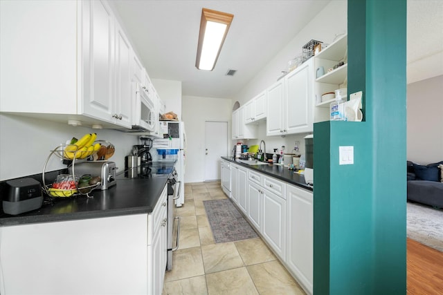 kitchen with sink, white cabinets, light tile patterned flooring, and stainless steel electric range